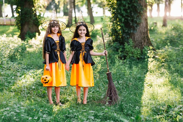 Des filles souriantes en costumes de sorcière dans un parc verdoyant et ensoleillé