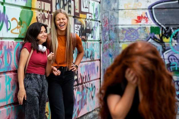 Photo gratuite filles souriantes à coup moyen intimidant un adolescent