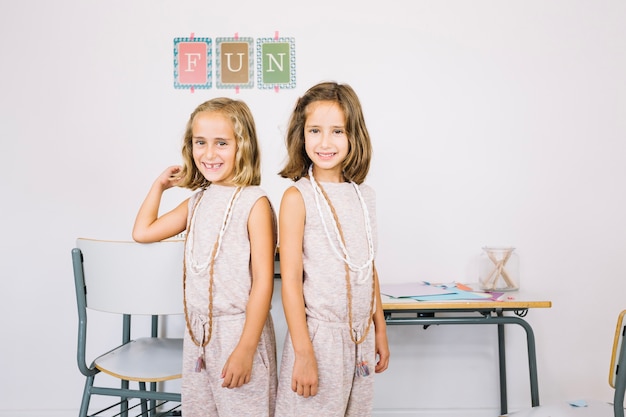 Filles souriantes posant près de tables