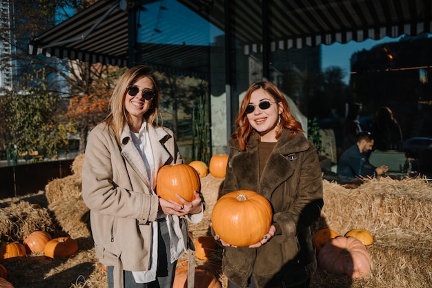 Les filles tiennent les citrouilles dans les mains