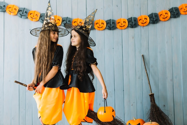 Filles en vêtements de sorcière et chapeaux pointus assis sur un balai