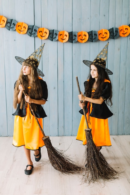 Filles en vêtements de sorcière tenant des balais