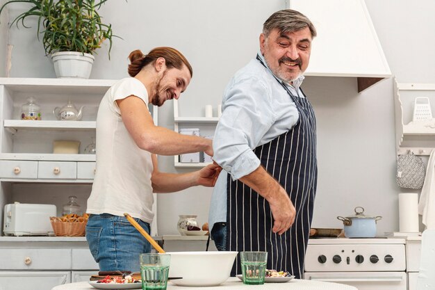 Fils aidant père avec tablier de cuisine