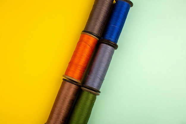 Photo gratuite fils multicolores pour la couture sur un sol jaune-vert