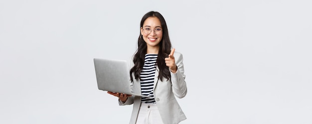 Finance d'entreprise et emploi concept d'entrepreneurs féminins prospères Souriant heureux femme d'affaires louange collègue qui a fait un bon point pointant le doigt caméra satisfait tenir ordinateur portable