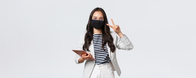 Finance d'entreprise et emploi covid19 empêchant le virus et le concept de distanciation sociale Enthousiaste jeune employée de bureau asiatique femme entrepreneur avec tablette numérique dans un masque de protection