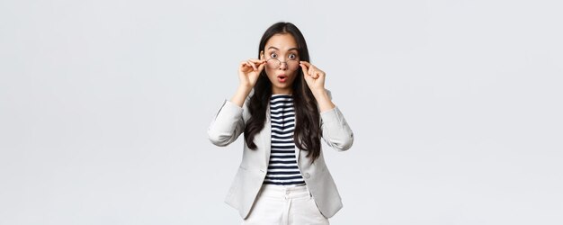 Finance d'entreprise et entrepreneur d'emploi et concept d'argent Une femme de bureau asiatique choquée décolle des lunettes et écarquille les yeux alors qu'elle entend de grandes nouvelles haletant debout fond blanc