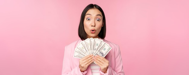 Financer Le Microcrédit Et Le Concept De Personnes Heureuse Femme D'affaires Asiatique Souriante Montrant De L'argent En Dollars Debout En Costume Sur Fond Rose