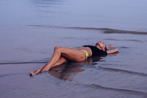 Fit bronzé jeune femme caucasienne en mer au coucher du soleil