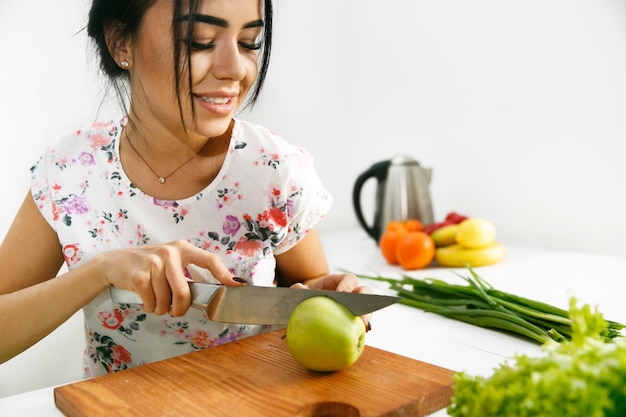 Fit brunette coupe pomme verte sur une planche de bois dans la cuisine