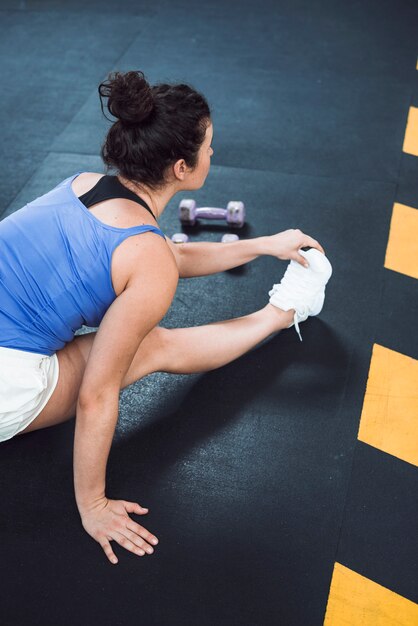 Fit femme qui s'étend de la jambe dans un club de fitness