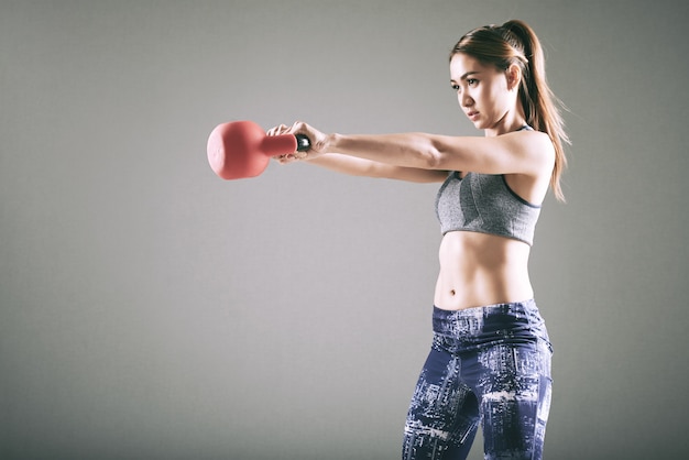 Fit la jeune femme asiatique exerçant avec kettlebell