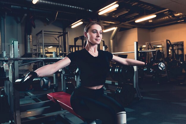 Fit la jeune femme faire des exercices avec haltère dans un centre de fitness