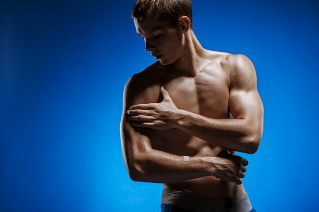 Fit le jeune homme avec un beau torse sur le mur bleu