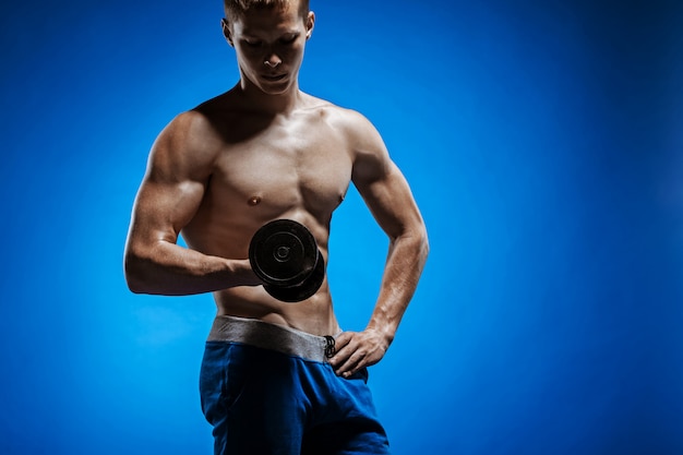 Fit le jeune homme avec un beau torse sur le mur bleu