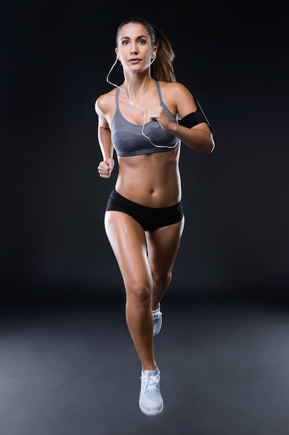 Fit et sportive jeune femme qui court sur fond noir.