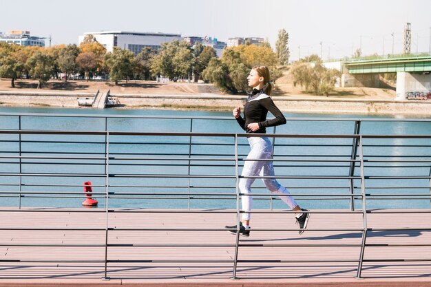 Fitness coureur féminin sportif en bonne santé en cours d&#39;exécution près du lac