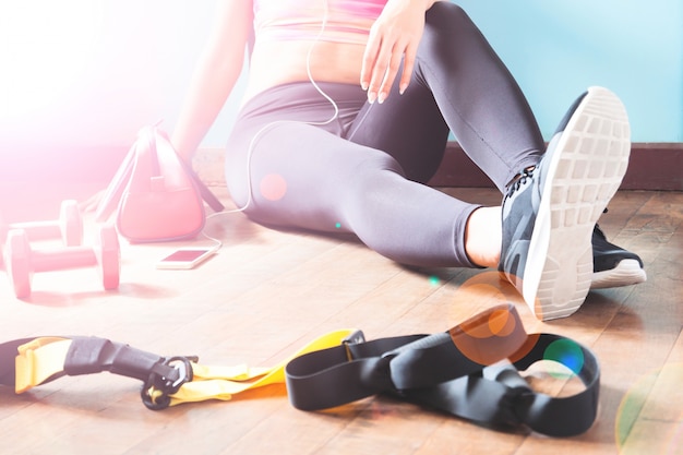 Photo gratuite fitness féminin reposant et relaxant après la séance d'entraînement. femme assise sur le parquet. sport, fitness, mode de vie sain