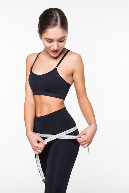 Fitness femme mesurant la forme parfaite de belles hanches isolé sur mur blanc. Concept de modes de vie sains