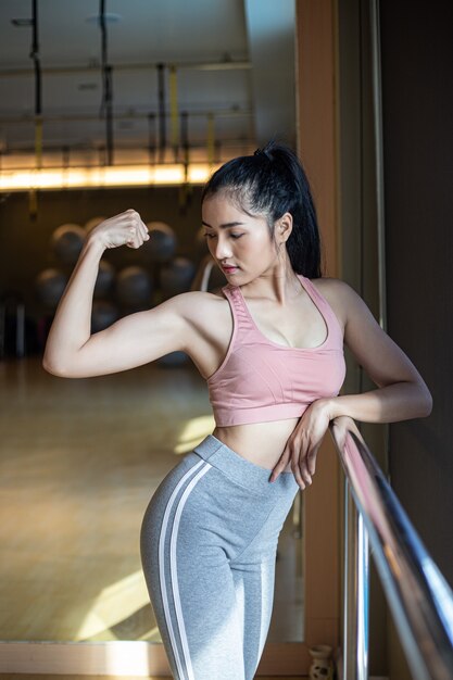 Fitness femmes montrent les muscles des bras dans la salle de gym.