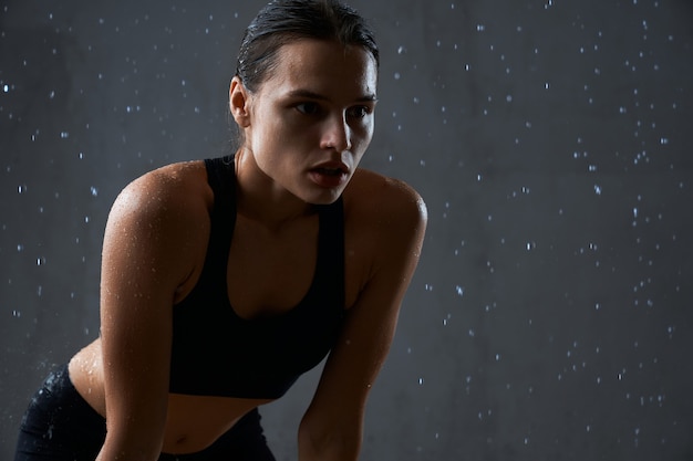 Fitnesswoman tenant les mains sur les genoux sous la pluie