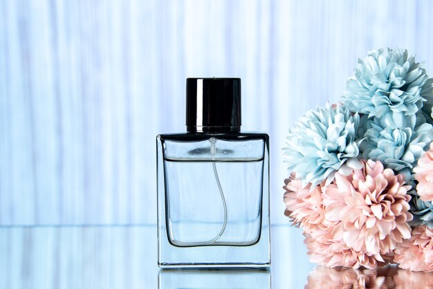 Flacon de parfum élégant vue de face et fleurs colorées sur fond bleu clair