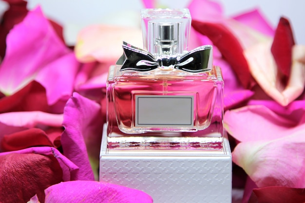 Flacon de parfum vue de face sur boîte avec pétales de rose rose