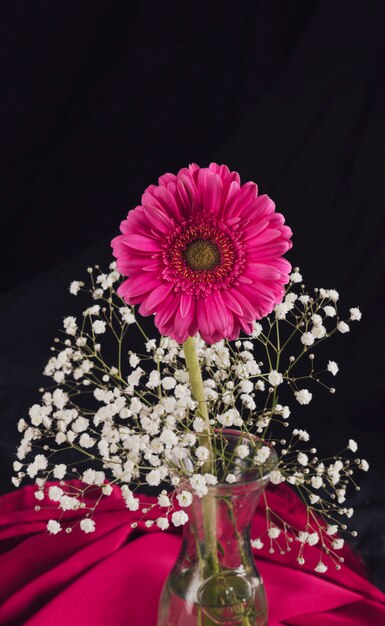 Fleur avec des brindilles de fleurs dans un vase près de textile rose dans l&#39;obscurité