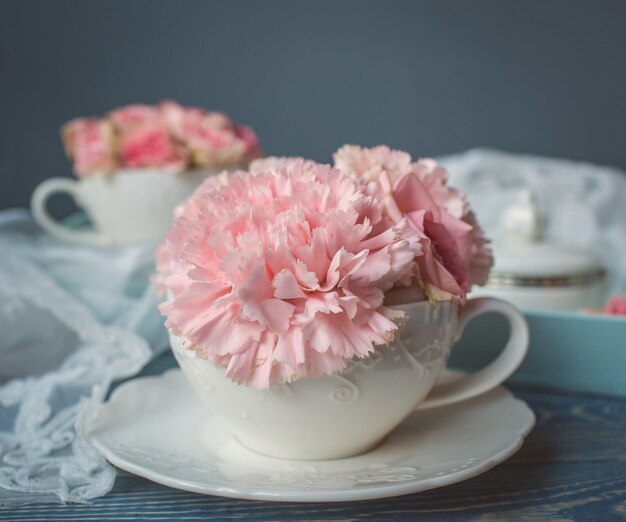 Fleur rose posée sur le dessus des tasses blanches.