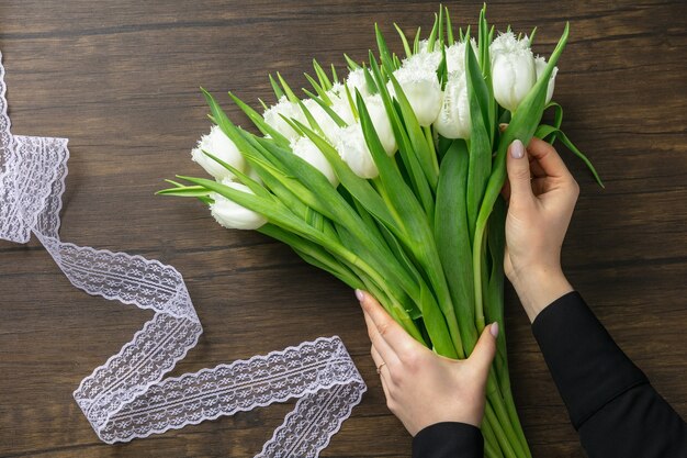 Fleuriste au travail. femme faisant un bouquet moderne de mode de différentes fleurs sur fond en bois.