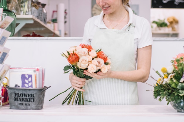 Fleuriste de culture tenant le bouquet près du comptoir
