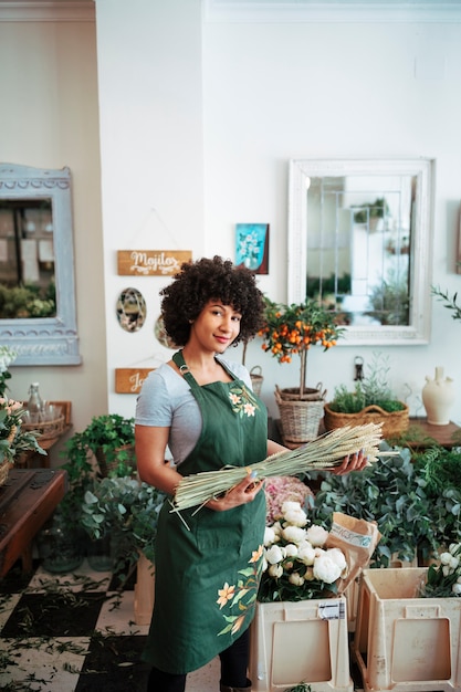 Fleuriste debout dans une boutique tenant un bouquet d&#39;épillets