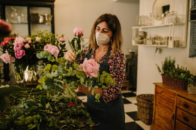 Fleuriste européenne avec un masque médical faisant des arrangements floraux