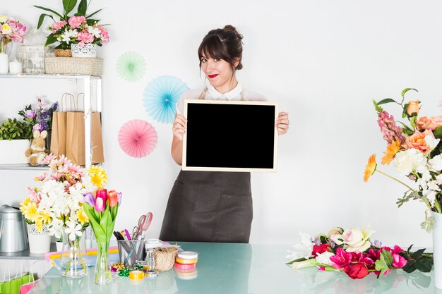 Fleuriste femme avec une ardoise vierge, regardant la caméra