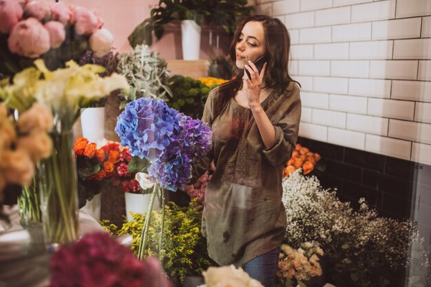 Fleuriste femme dans son propre magasin de fleurs en prenant soin de fleurs