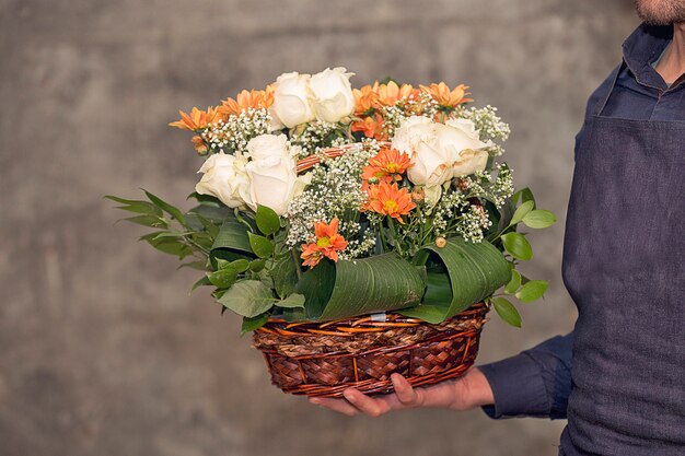 Fleuriste mâle promouvant un bouquet de fleurs à l'intérieur du panier.