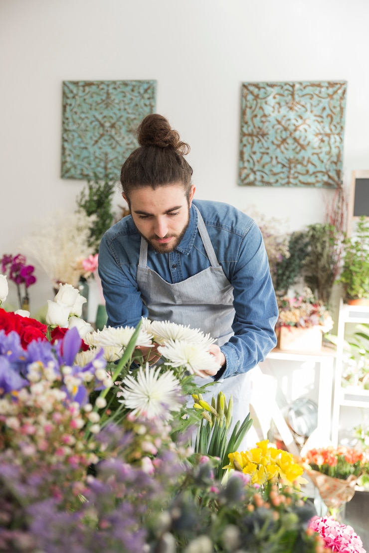 Photo gratuit fleuriste mâle regardant une belle fleur blanche dans la boutique