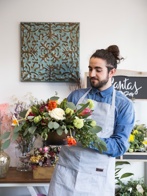 Un fleuriste mâle regardant une décoration florale dans son magasin