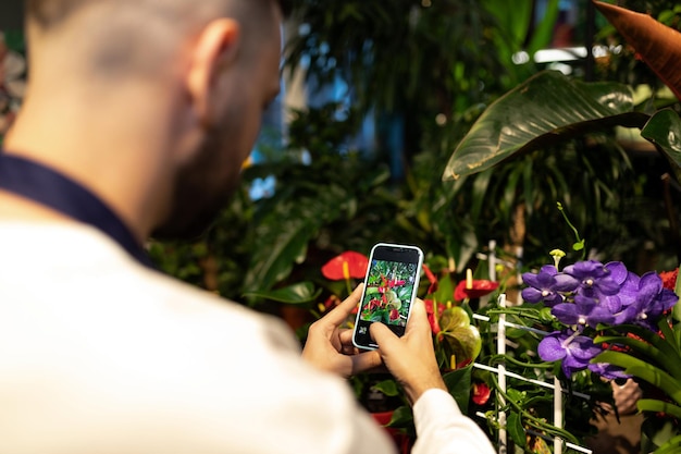 Le fleuriste photographie des fleurs au téléphone en vente dans la boutique en ligne