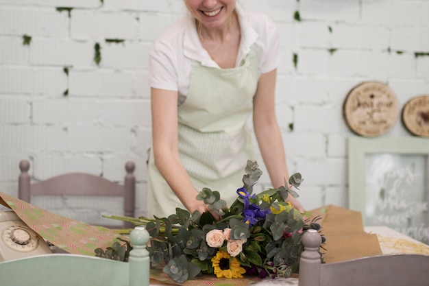 Photo gratuite fleuriste souriant enveloppant le bouquet