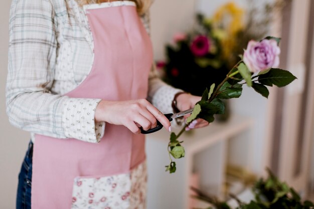 Fleuriste en tablier préparant la rose