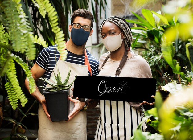 Fleuristes en masque facial avec signe ouvert pendant la nouvelle normalité