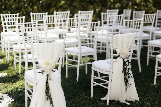 Fleurs blanches avec des branches vertes décorent des chaises