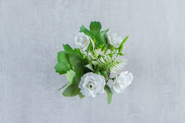 Fleurs blanches fraîches dans une cruche en bois, sur la table blanche.