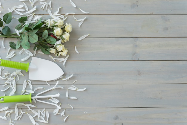 Fleurs blanches, petite truelle et râteau sur un bureau en bois gris