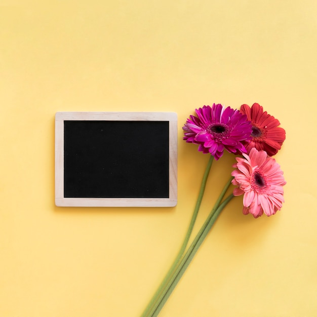 Photo gratuite fleurs colorées à côté de l'ardoise