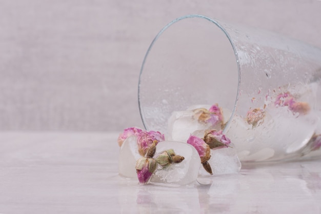 Fleurs congelées dans des glaçons sur une surface blanche.