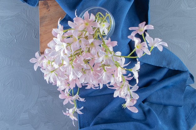 Fleurs élégantes dans une cruche sur une planche sur le morceau de tissu, sur fond blanc. photo de haute qualité