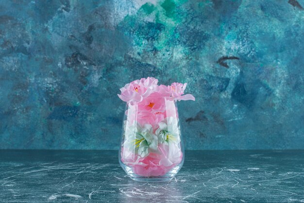 Fleurs fraîches et élégantes dans un verre, sur la table bleue.