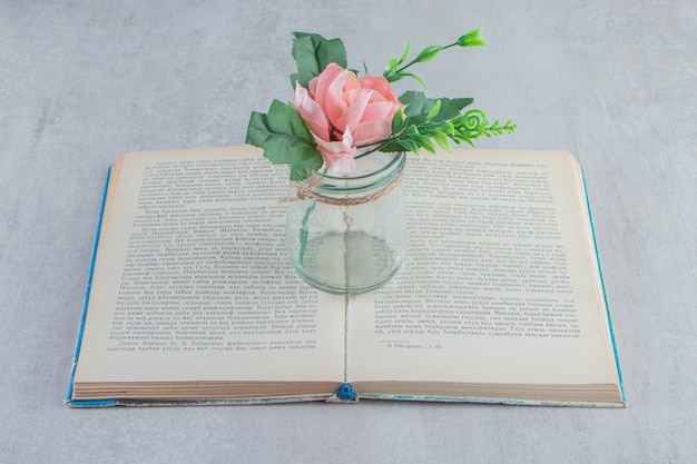 Photo gratuite fleurs gracieuses dans un pot sur le livre, sur le tableau blanc.